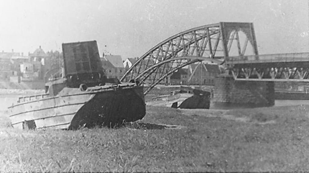 Zwei amerikanische Amphibienfahrzeuge (GMC DUKW, "Duck") auf der Grünewalder Seite. Im Hintergrund die zerstörte Elbbrücke“ im Jahr 1945.
