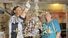 Christina Neubacher (von links), Karl Eisbein und Theresia Gebauer betrachten den Kronleuchter in der Stadtkirche von Jerichow, der für die Reinigungsarbeiten tiefer gehängt wurde, um alle Teile erreichen und dokumentieren zu können. 
