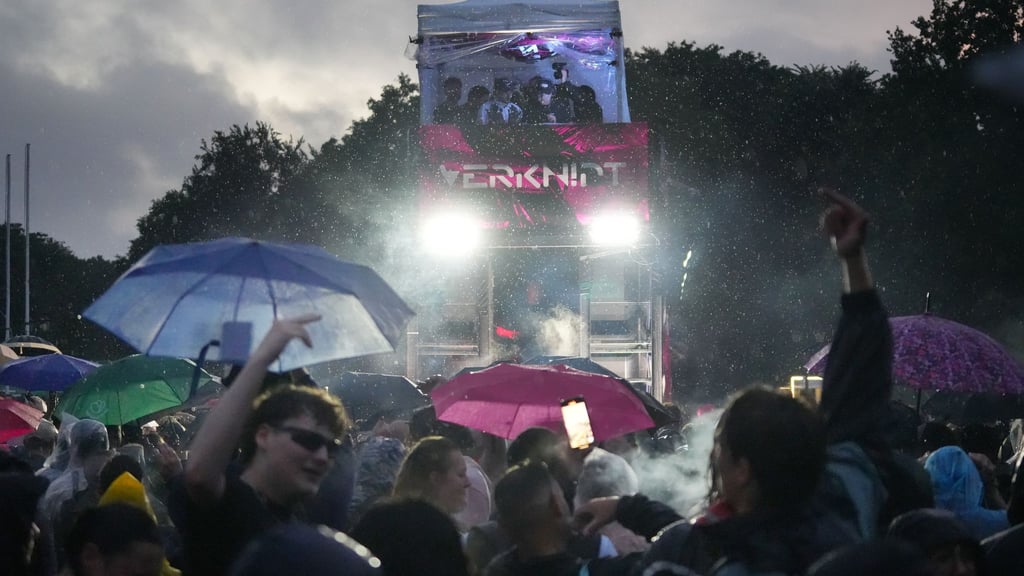 Menschen tanzen trotz starkem Regen in der späten Abenddämmerung bei der Techno-Parade „Rave The Planet“.