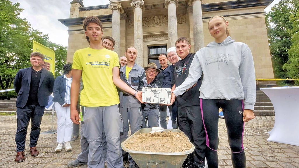 Leonhard Lehmann (li.) vom scheidenden Jugendbauhütten-Team übergibt den symbolischen Staffelstein an Meret Gerlach vom neuen Team.