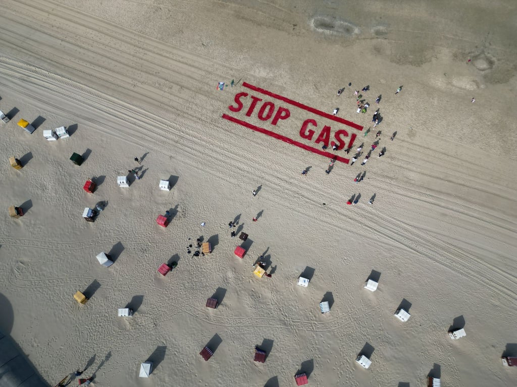 Klimaschutzaktivisten von Fridays for Future schreiben ihre Forderung nach einem Ende der Gasförderung auf den Strand der Insel Borkum.