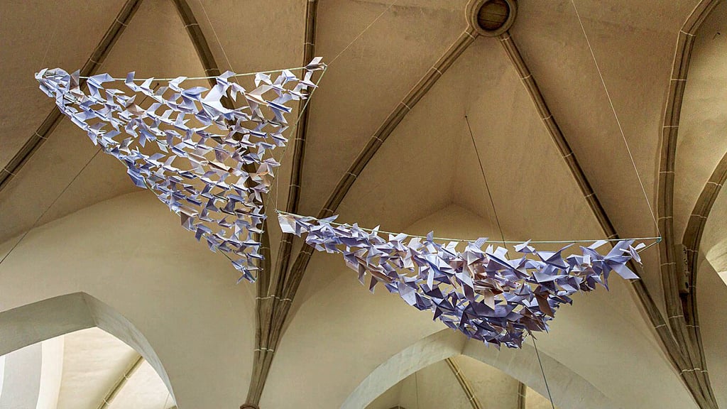 Aus vielen kleinen Friedenstauben entstanden zwei Schwärme, ein dritter soll folgen – moderne Kunst in der Michaeliskirche.