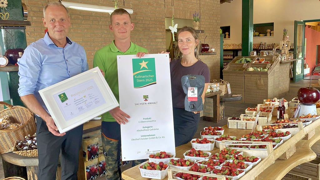 Wolfgang Hahn von der Agrarmarketing-Gesellschaft aus Magdeburg überbringt Marvin und Theresa Zwicker (alle v. li.) zwei Zeugnisse für den errungenen „Kulinarischen Stern 2025“, eine Urkunde für innen und das große Schild für die Außenfassade.