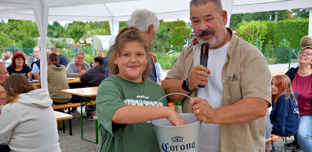 Glücksfee Mia zieht zum Sommerfest der Kleingartenanlage Salzwerke in Staßfurt die Gewinner am Lostopf vom Vereinsvorsitzenden Ingo Knabe.