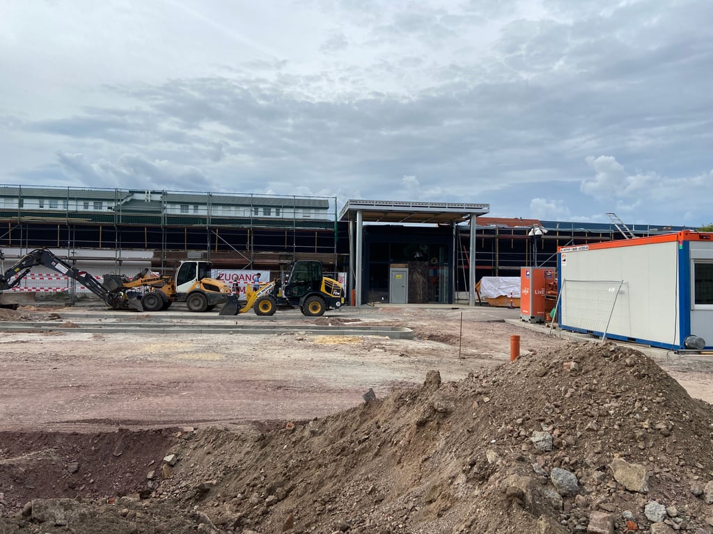 Blick auf die Baustelle an der Spielhagenstraße in Magdeburg: Vor dem halbfertigen Rewe-Markt prägt derzeit noch schweres Gerät und aufgerissener Boden das Bild – bis zur Wiedereröffnung soll hier ein neuer Parkplatz entstehen.
