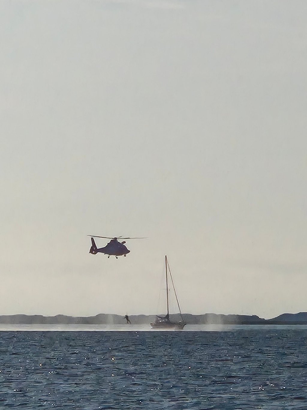 Vor der Insel Spiekeroog bringt ein Hubschrauber einen Sanitäter an Bord eines Segelboots.