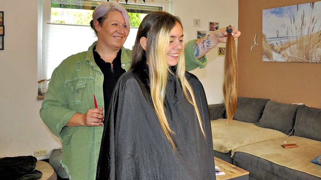 Friseurin Jennifer Eiling (links) präsentiert Amalia ihre abgeschnittene Haarpracht. Diese möchte die Gymnasiastin der Deutschen Krebshilfe zur Herstellung einer hochwertigen Echthaar-Perücke spenden.