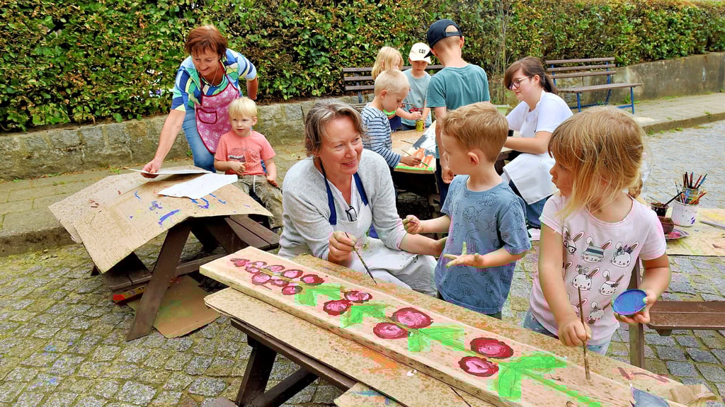 Künstlerin Heike Wolff (vorn) schlug den Kindern in Abberode vor, eine Zaunlatte mit einem Rosenstock zu verzieren. Gemeinsam gingen sie an Werk.