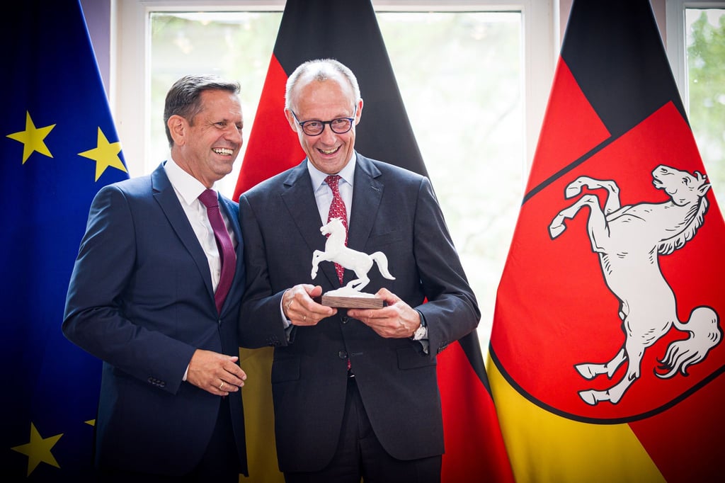 Ein Ross für den Kanzler: Lies (l) überreicht Merz eine Pferdeskulptur – passend zur Krawatte mit Landeswappen-Motiv.
