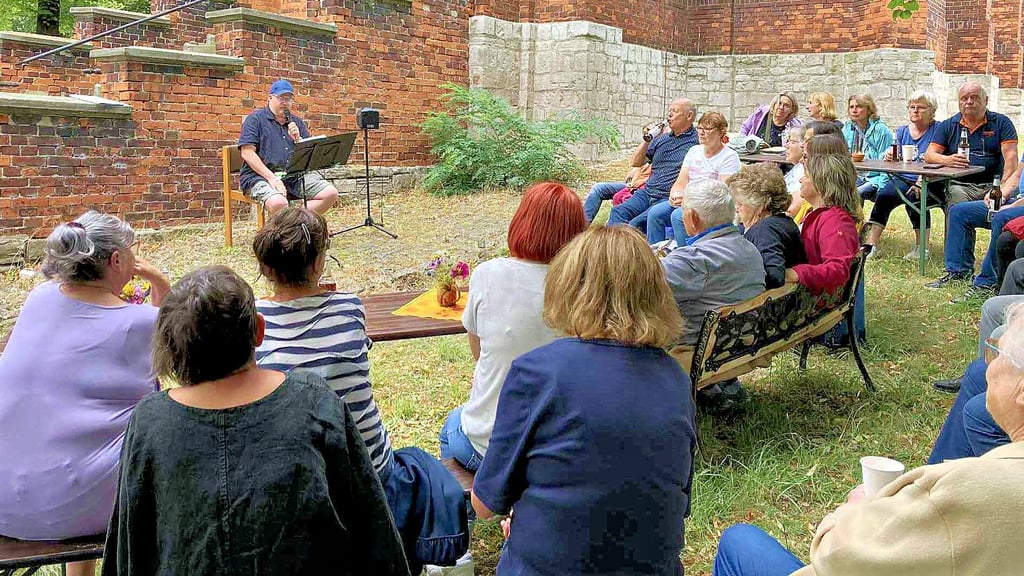 Der Schackstedter Kirchensommer ist nach draußen gezogen: Neben der Kirchentreppe liest Jochen Reinecke humorvolle Geschichten vor.