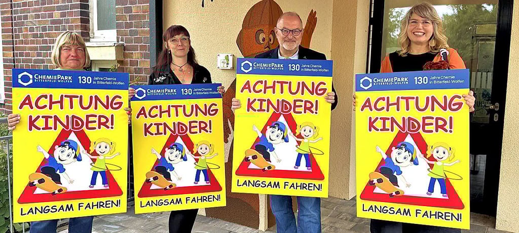 Chemiepark GmbH-Geschäftsführer Kai Uwe Krauel und Sandra Greiner, Verantwortliche für Öffentlichkeitsarbeit der Chemiepark GmbH (r.), überreichen die Schilder an die Kita „Campus Kids“.
