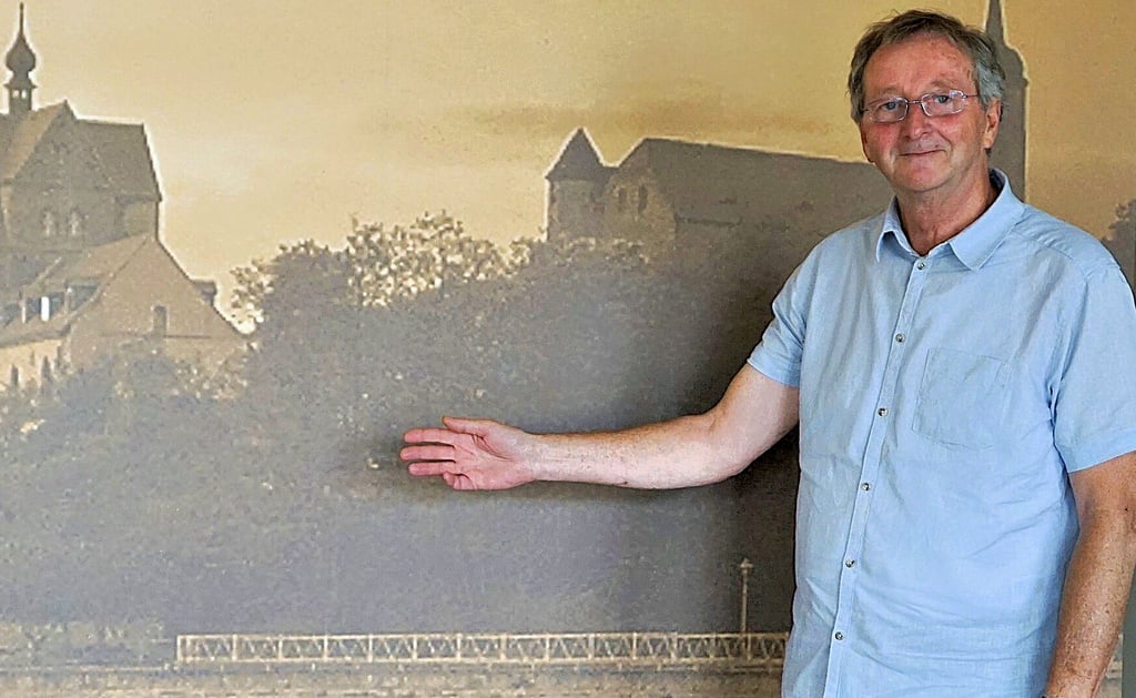 Günter Saken vor der Fototapete im Dorfgemeinschaftssaal, die einen Uferabschnitt des Süßen Sees zeigt.