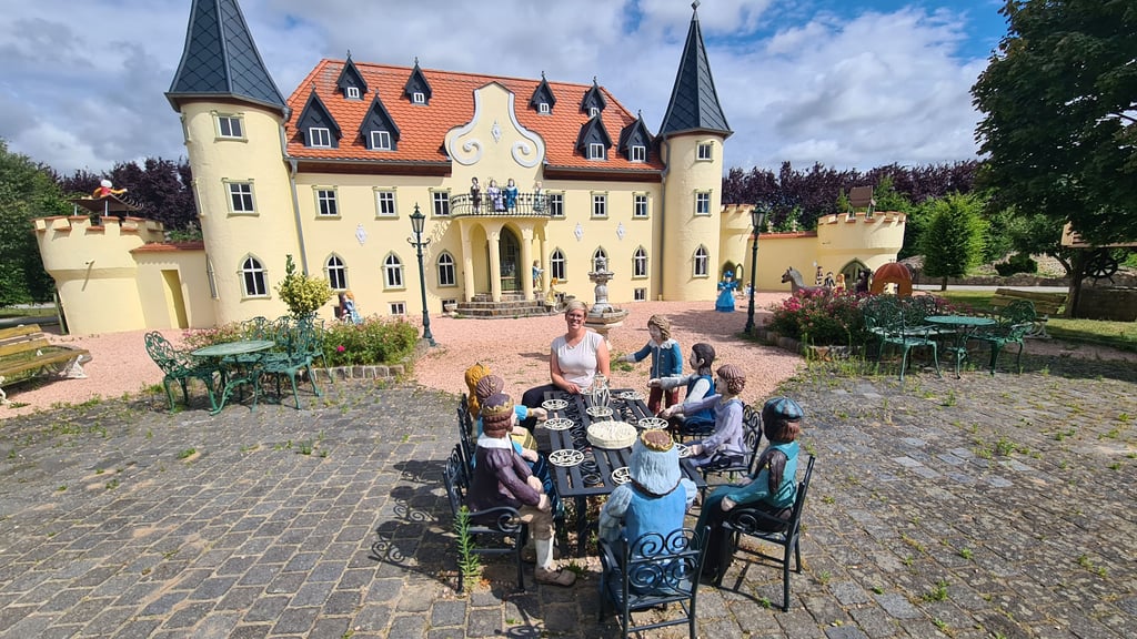 Charlotte Valdiek, Geschäftsführerin des "Märchenparks und Duftgartens" Salzwedel, vor dem Schloss an einem königlichen Tisch mit Figuren.