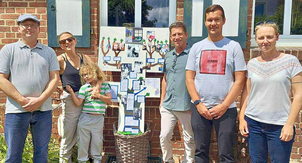 Mit dem Familienstammbaum begrüßten Florian Sajontz (links) und Aileen Lemme (rechts) vom Heimat- und Schifferverein sowie Ortsbürgermeister Alexander Wittwer die Nachfahren von Ernst Lewy in Bittkau. Alisa und Daniel Lee waren mit Söhnchen Magnys aus Amerika gekommen.