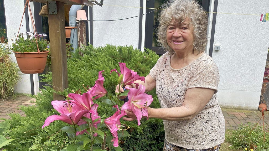 Ingrid Fritzsche mit der wunderbar blühenden großen Lilie im Hof ihres Grundstückes in Jessen.