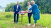 Bürgermeister Bernhard Hieber enthüllt mit  Julia Würth  (mitte)  von der Agrarfachschule und  Anita Kirmer von der Hochschule Anhalt die Infotafel zum Wildblumenwiesen-Projekt.