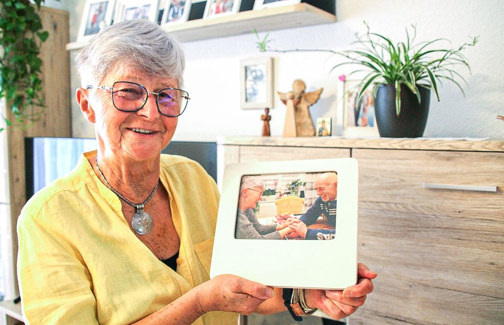 Karin Stork-Vorwerk mit dem Bild von sich und ihrem Mann, der noch im Krankenhaus ist. Und mit Schutzengel-Figuren hinter sich.