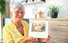 Karin Stork-Vorwerk mit dem Bild von sich und ihrem  Mann, der noch im Krankenhaus ist. Und mit Schutzengel-Figuren hinter sich. 