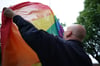 Ein Justizvollzugsbeamter hisst die Regenbogenfahne vor einem Hamburger Gefängnis. Rechte qeerer Gefangener werden öffentlich kontrovers debattiert. 