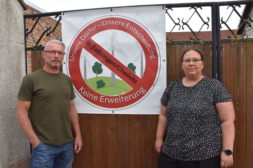 Uwe Mayer und Rebecca Zenker von der Bürgerinitiative (BI) Zethlingen/Cheinitz vor dem Transparent mit BI-Logo, das jetzt an vielen Häuserfronten hängt.