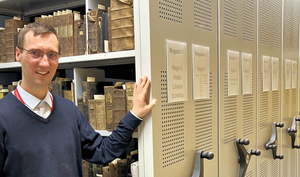 Leitet das Kirchenkreisarchiv: André Junghänel steht vor Büchern und anderen Materialien aus Wettin.