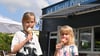 Die Geschwister Aria (9) und Ella (7) lassen sich bei sommerlichen Temperaturen ihr Eis an der Eisdiele Pinguin in Neu Olvenstedt schmecken. 