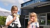 Die Geschwister Aria (9) und Ella (7) lassen sich bei sommerlichen Temperaturen ihr Eis an der Eisdiele Pinguin in Neu Olvenstedt schmecken. 