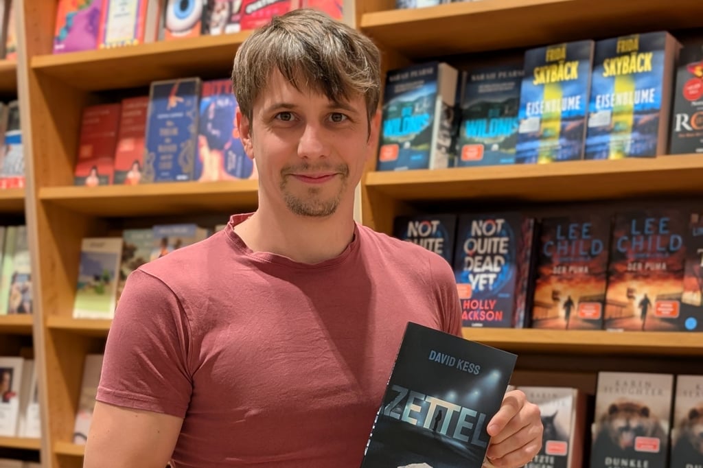 Autor David Katzenellenbogen (alias David Kess) mit seinem Roman „Zettel“ in einer Buchhandlung.