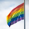 Ein Justizvollzugsbeamter hisst die Regenbogenfahne vor einem Hamburger Gefängnis. Rechte qeerer Gefangener werden öffentlich kontrovers debattiert. 