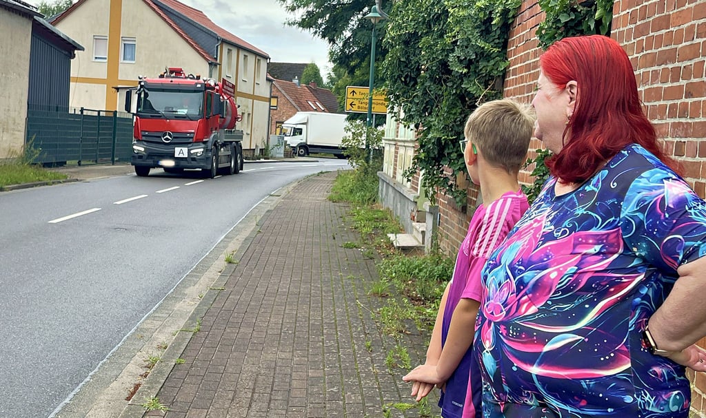 Martina Schulze und Enkel Sidney an der Kurve vor ihrem Haus. Die Fahrbahn ist schmal und stark befahren. Schulkinder müssen sie täglich kreuzen. Trotzdem gibt es keine Geschwindigkeitsbeschränkung.