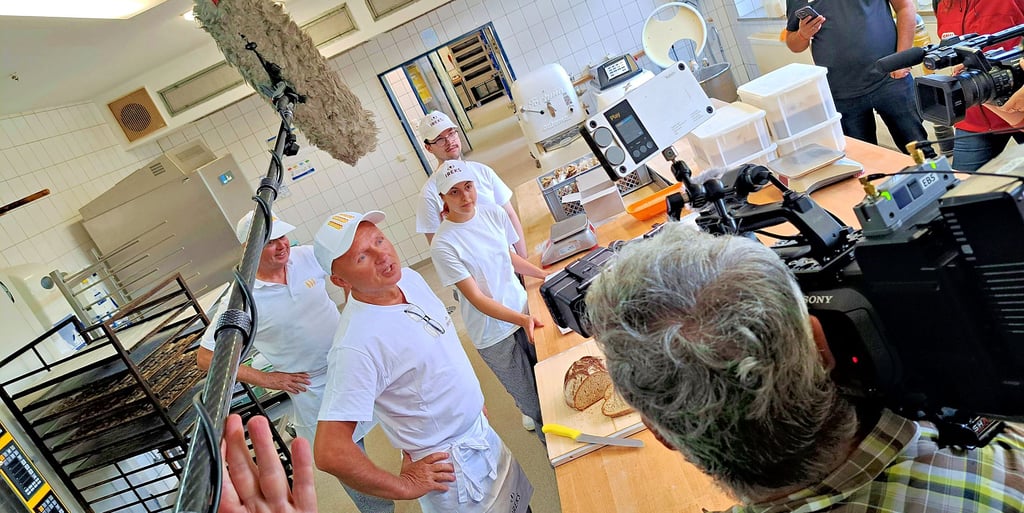 Bäckermeister Mike Schulze (2.v.li.) erklärt im Beisein seines Meisterkollegen Uwe Worch und der Lehrlinge Lea Marie Bohn und Justin Thiele den Medien, wie das Bärlauchbrot, das den „Kulinarischen Stern 2025“ in Sachsen-Anhalt gewonnen hat, entsteht.
