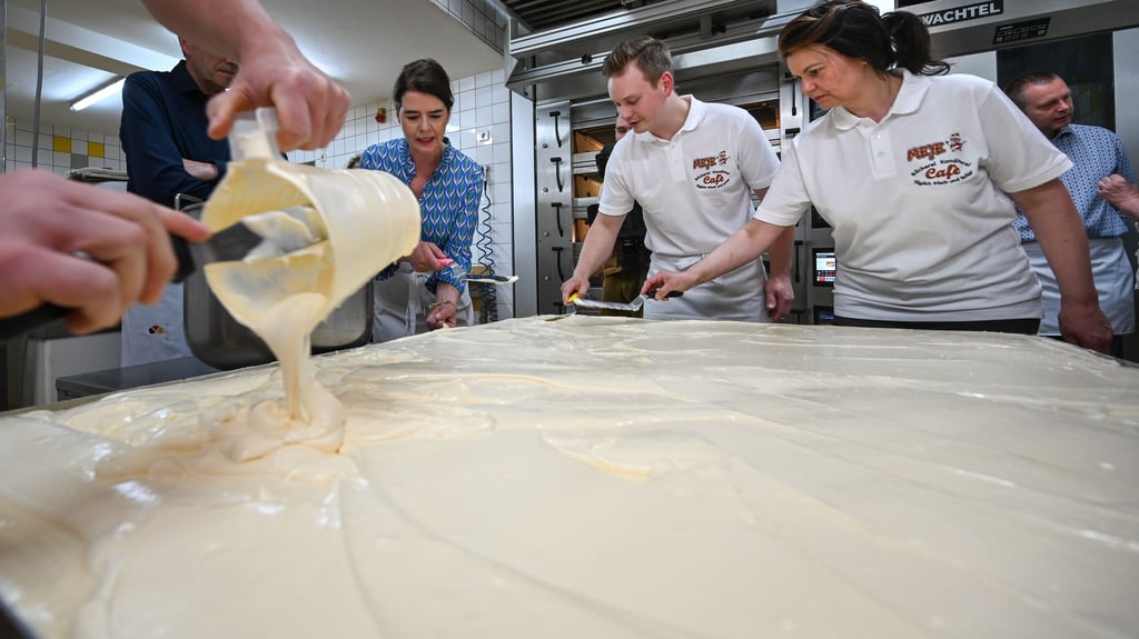 Susanne Daubner (2.v.l), Tagesschau-Sprecherin, Vincent Richter (M) und Bianca Richter von der Bäckerei Meye verteilen auf dem weltgrößten Mohnkuchen den Belag. Der Rekordversuch war eine Aktion der Kunststiftung Sachsen-Anhalt anlässlich des Gedenkjahres „500 Jahre Bauernkrieg und 500. Todestag von Thomas Müntzer“ im Jahr 2025. In Allstedt hielt Müntzer 1524 auf dem Schloss seine berühmte Fürstenpredigt. picture alliance/dpa