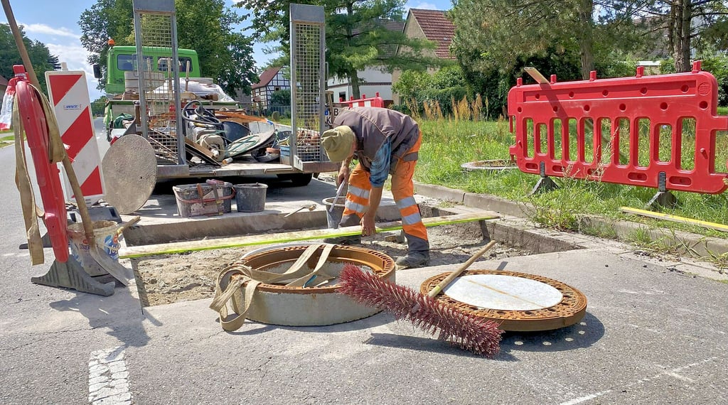 Thomas Mende bearbeitet die Gullideckel in Gerbisbach, damit starten die Straßenbauarbeiten an der Durchfahrtsstraße.