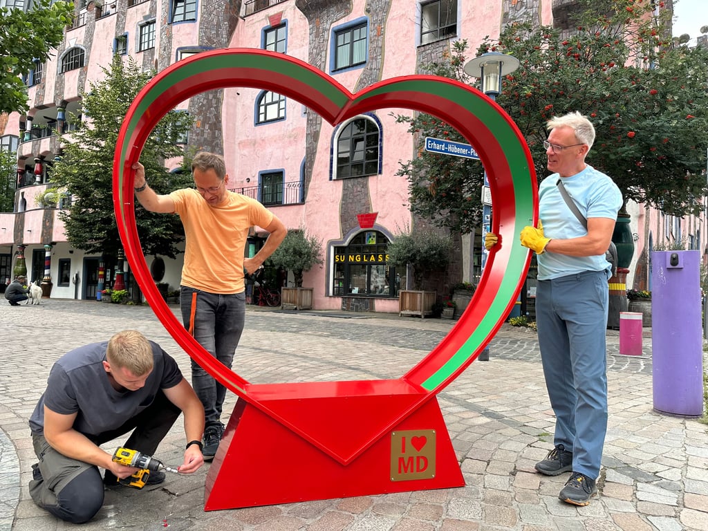 In den Farben des SCM steht nun ein Herz vor dem Hundertwasserhaus. Ben Bormann, Christian Gülck und Arno Frommhagen (v. l.) von der IG Innenstadt bauten sie am 31. Juli 2025 auf.