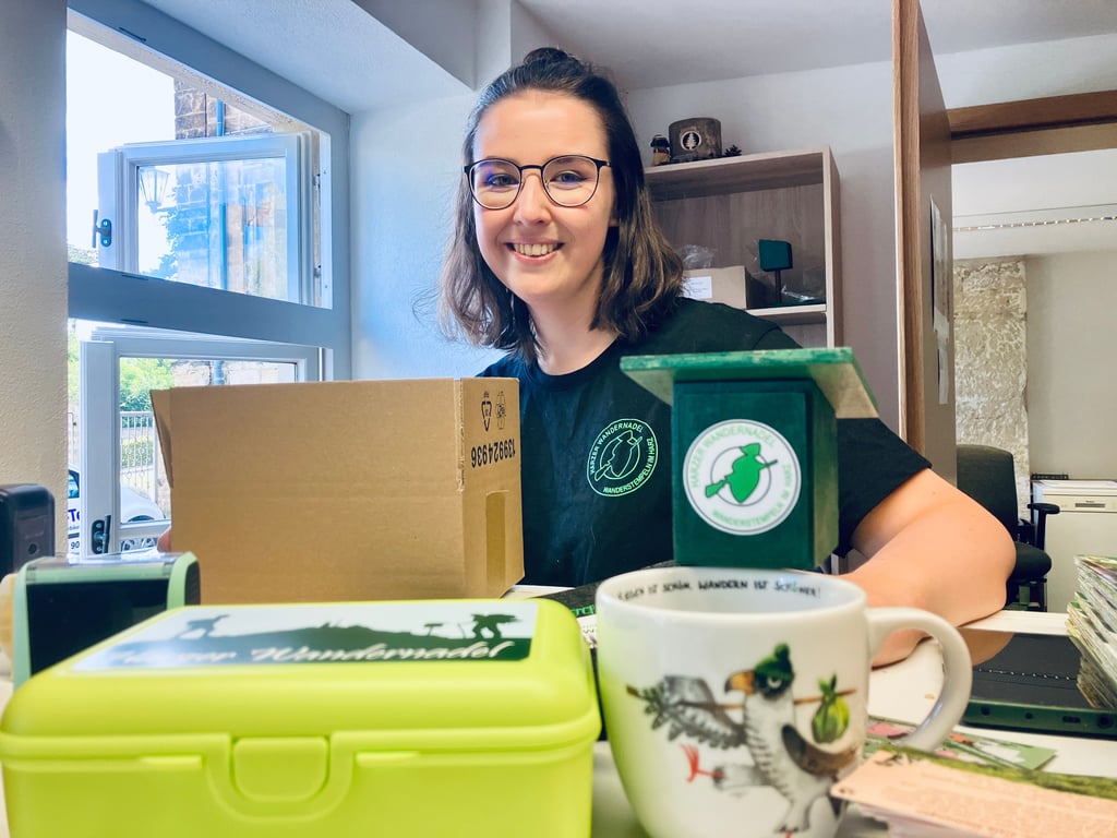 Wandernadel-Mitarbeiterin Charlotte Jacobs packt ein Paket mit Wandernadel-Produkten.