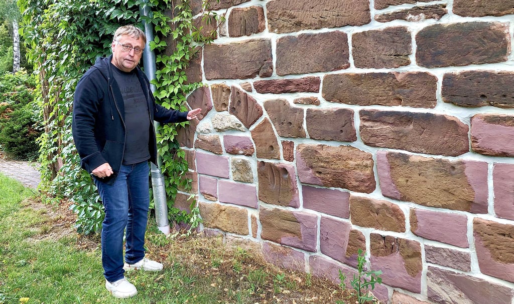 Lutz Geweniger weist auf die ältesten Teile der Kirche hin. Die roten Steine stammen aus der Anfangszeit des Kirchenbaus.