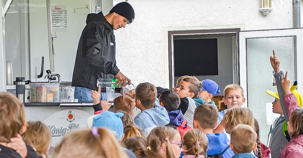 Geduldig schenkt Andrej am Getränkewagen den Hortkindern ihre Getränke ein, bevor es los geht.