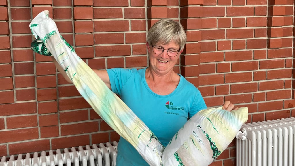 Carola Schulz zeigt einen selbstgemachten Sack, der mit Kirschkernen gefüllt und recht schwer ist. Wird er mit einer Hand angehoben, kullern die Kerne nach unten und man muss das andere Ende hochheben. Die Übung machen Menschen, die im Alltag oft nur eine Hand benutzen.