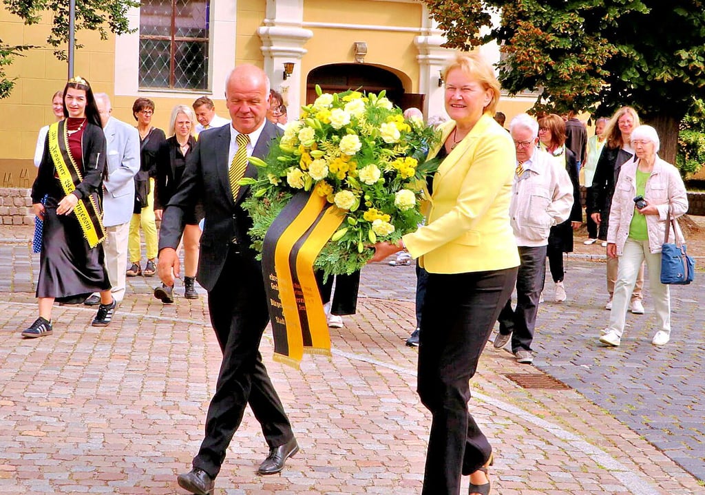Astrid Hage-Hamatschek und Kersten Henze tragen am Sonntag nach dem ökumenischen Gottesdienst in der Sankt-Nikolai-Kirche in Jessen den Kranz zum Denkmal auf dem Markt.