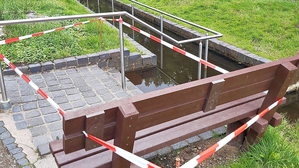 Stillstand am Kneipp-Becken: Die Wassertretstelle im Kalbenser Kurpark ist wegen eines Mauerbruchs seit Wochen gesperrt – das Absperrband signalisiert, dass hier derzeit kein Erfrischen im Storchengang möglich ist.