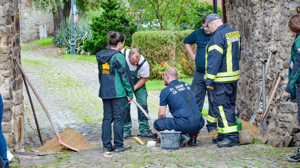 Michaela Wolf unterhält sich mit den Helfern der Feuerwehr, die den neuen Poller in der Einfahrt installieren.