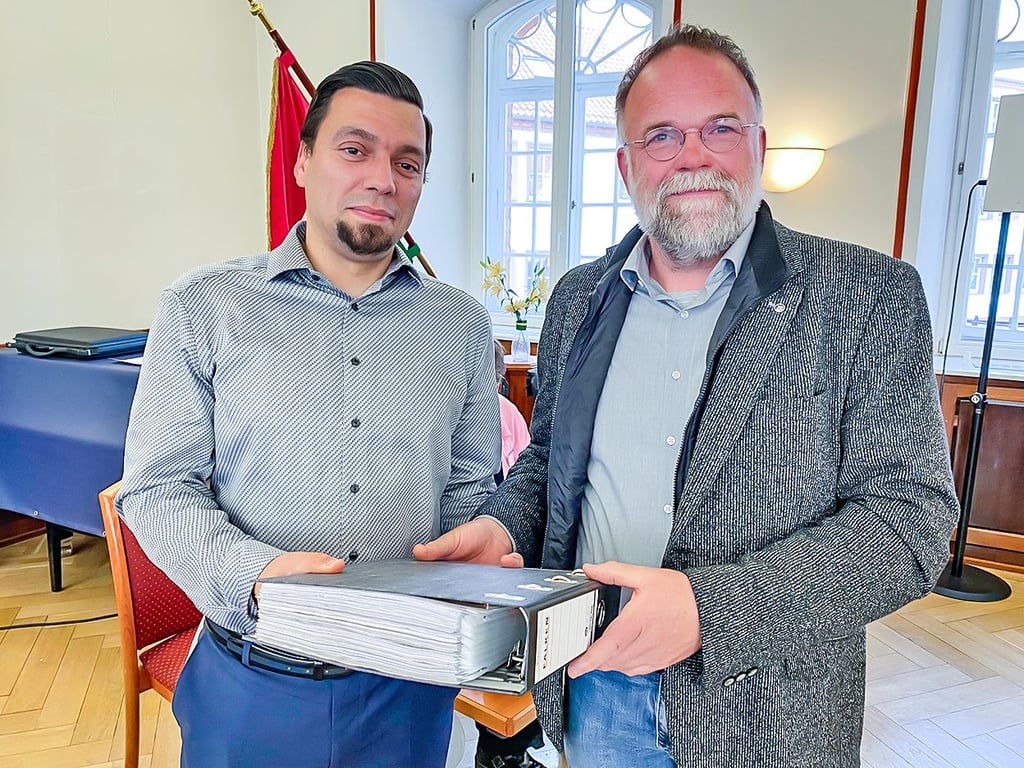 BI-Sprecher Ingolf Arndt (rechts) übergab in der Stadtratssitzung vom 26. Mai den dicken Ordner mit den über 4.000 Unterschriftenlisten gegen Windräder im Wald an Dezernatsleiter Andreas Hensel.