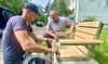 Patrick Krüger (v.l.) und Roger Warthemann montieren einen der Sitze an der Ernst-Barlach-Straße. 