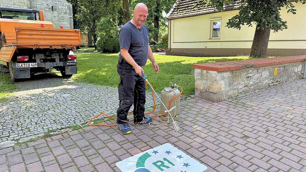 Ronny Weishaupt vom Hecklinger Stadtbaubetrieb brachte auf dem Fußweg vor der Kirche einen Hinweis auf die neue Radwegtrasse an.