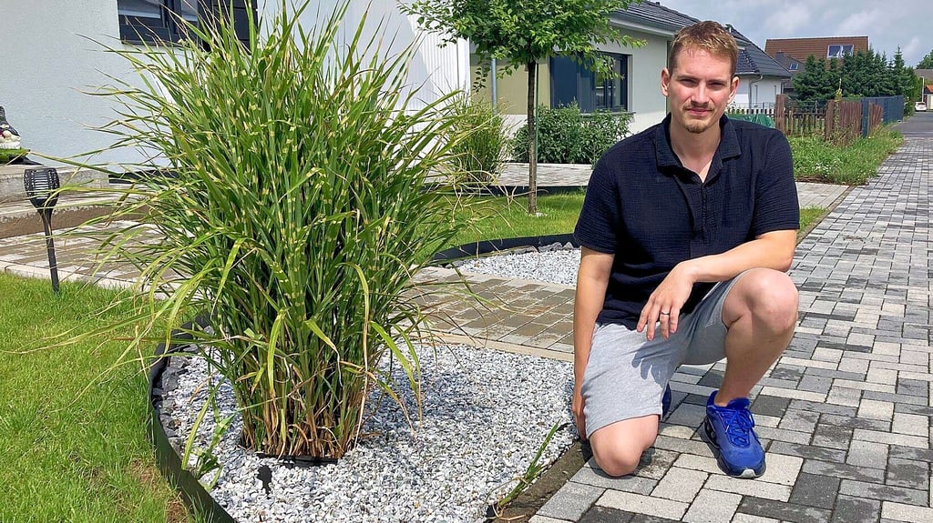 Adrian Herbst kniet vor seinem nun umgestalteten Vorgarten.
