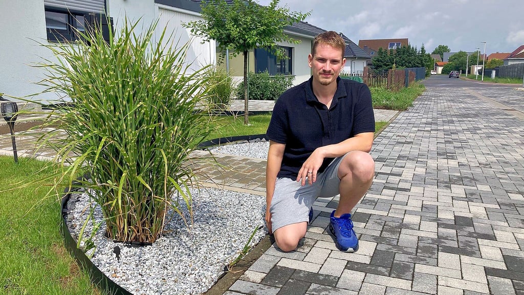 Adrian Herbst kniet vor seinem nun umgestalteten Vorgarten. Den früheren Steingarten musste er entfernen.