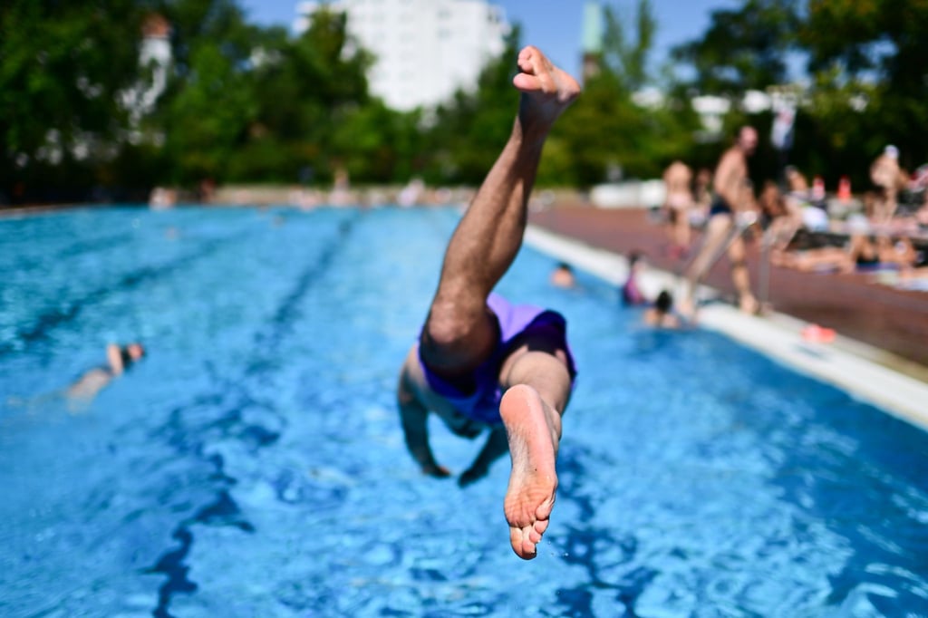 Ein Mann springt im Sommerbad Kreuzberg ins Becken.