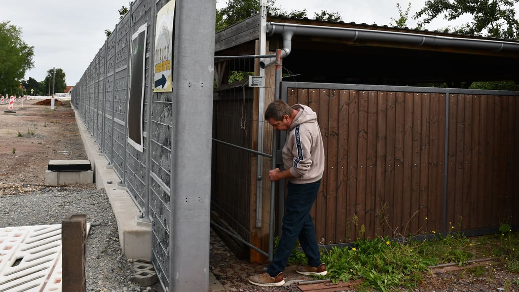 Der Magdeburger Olaf Kellner stellt provisorisch einen Bauzaun in die Lücke zwischen Sichtschutz und Carport, damit sein Hund nicht auf die Straße läuft.