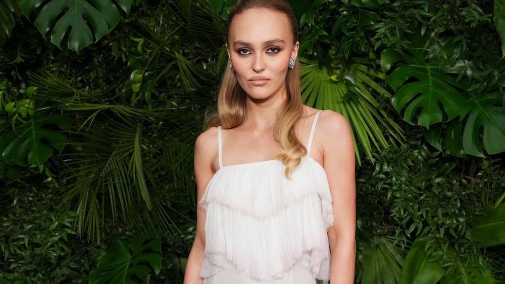 Schauspielerin Lily-Rose Depp schaut in typischer roter Teppich-Pose mit kühler Miene in die Kamera. (Archivbild)