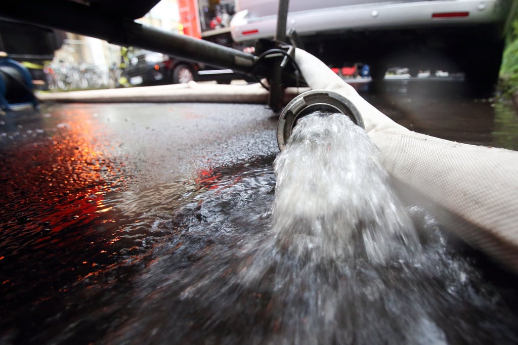 Feuerwehrleute pumpen Wasser aus.